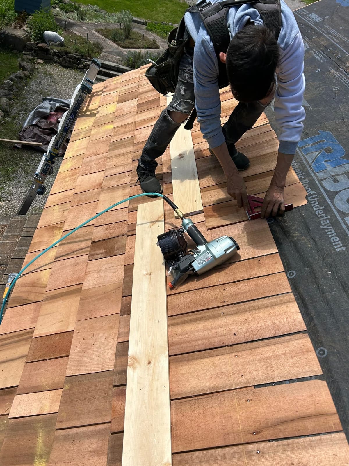 Crew installing cedar wood shingles on a roof