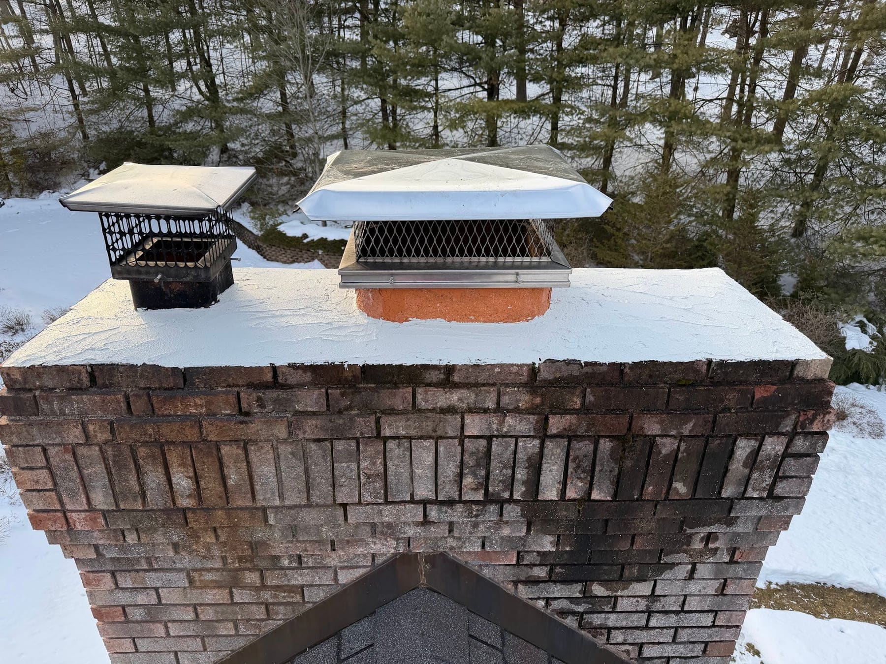 Two new chimney caps on a brick chimney in winter