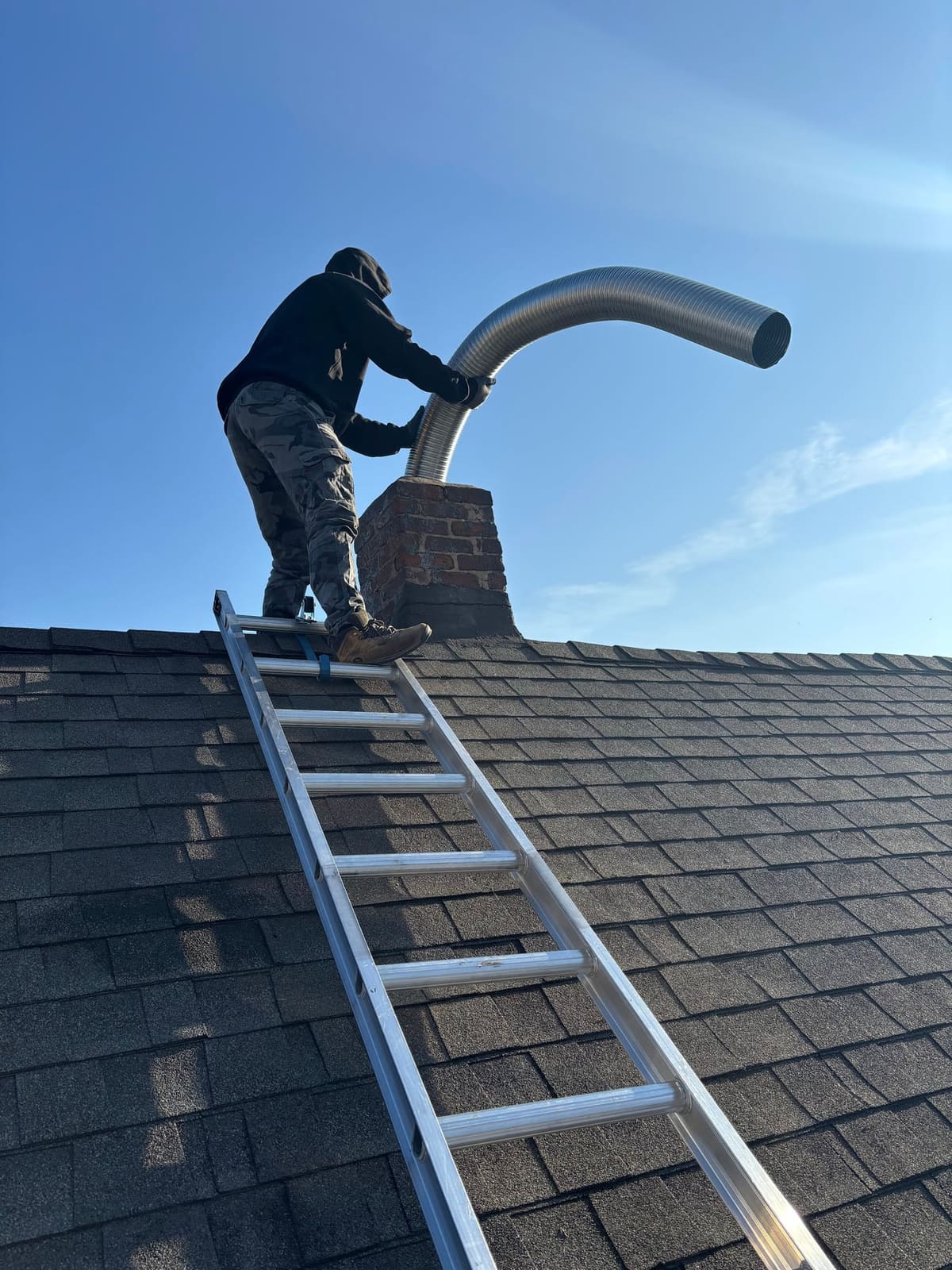 Technician feeding a stainless steel liner into a masonry chimney
