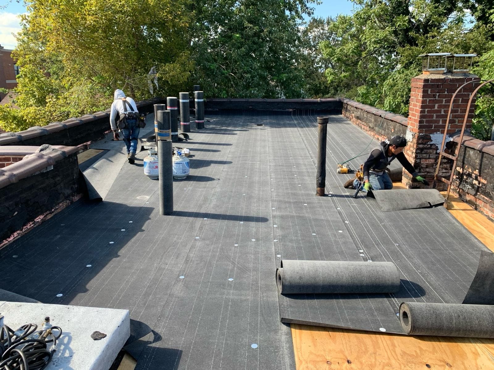 Crew rolling out new membrane on a flat roof replacement
