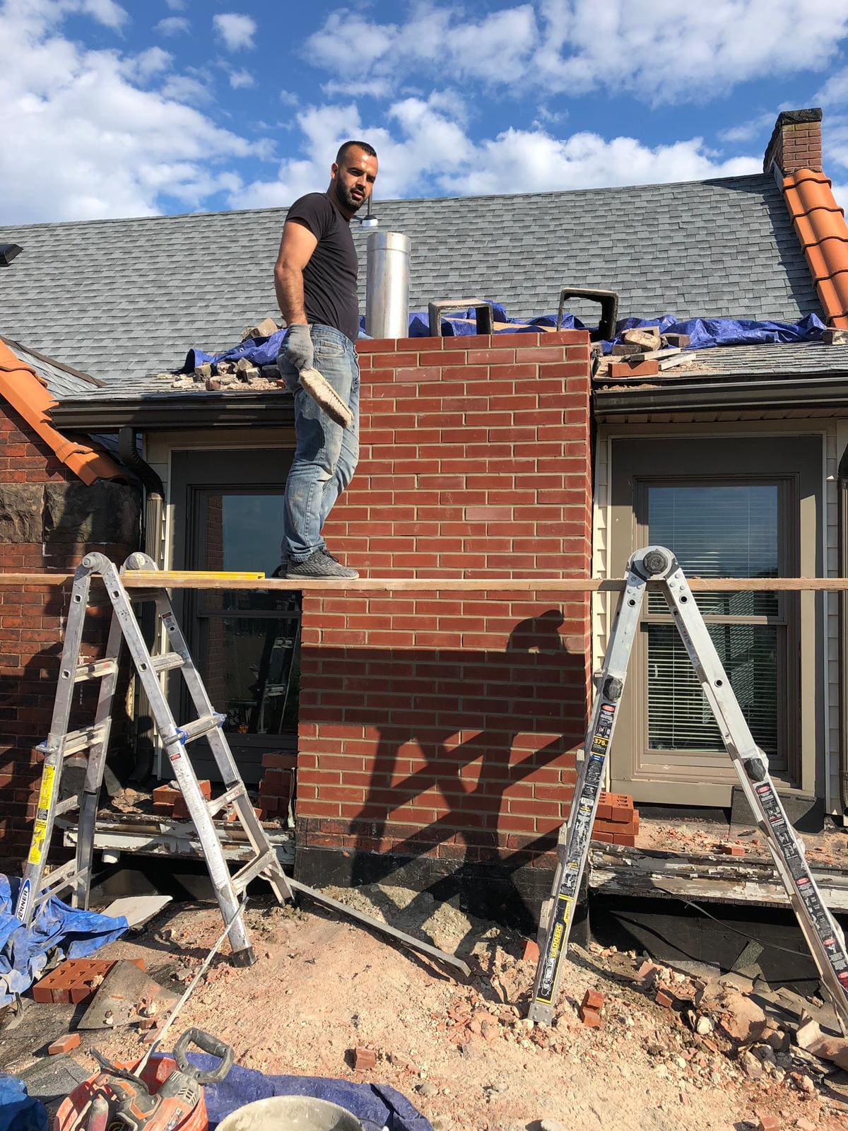 Asset mason rebuilding a brick chimney with a new stainless steel chimney liner