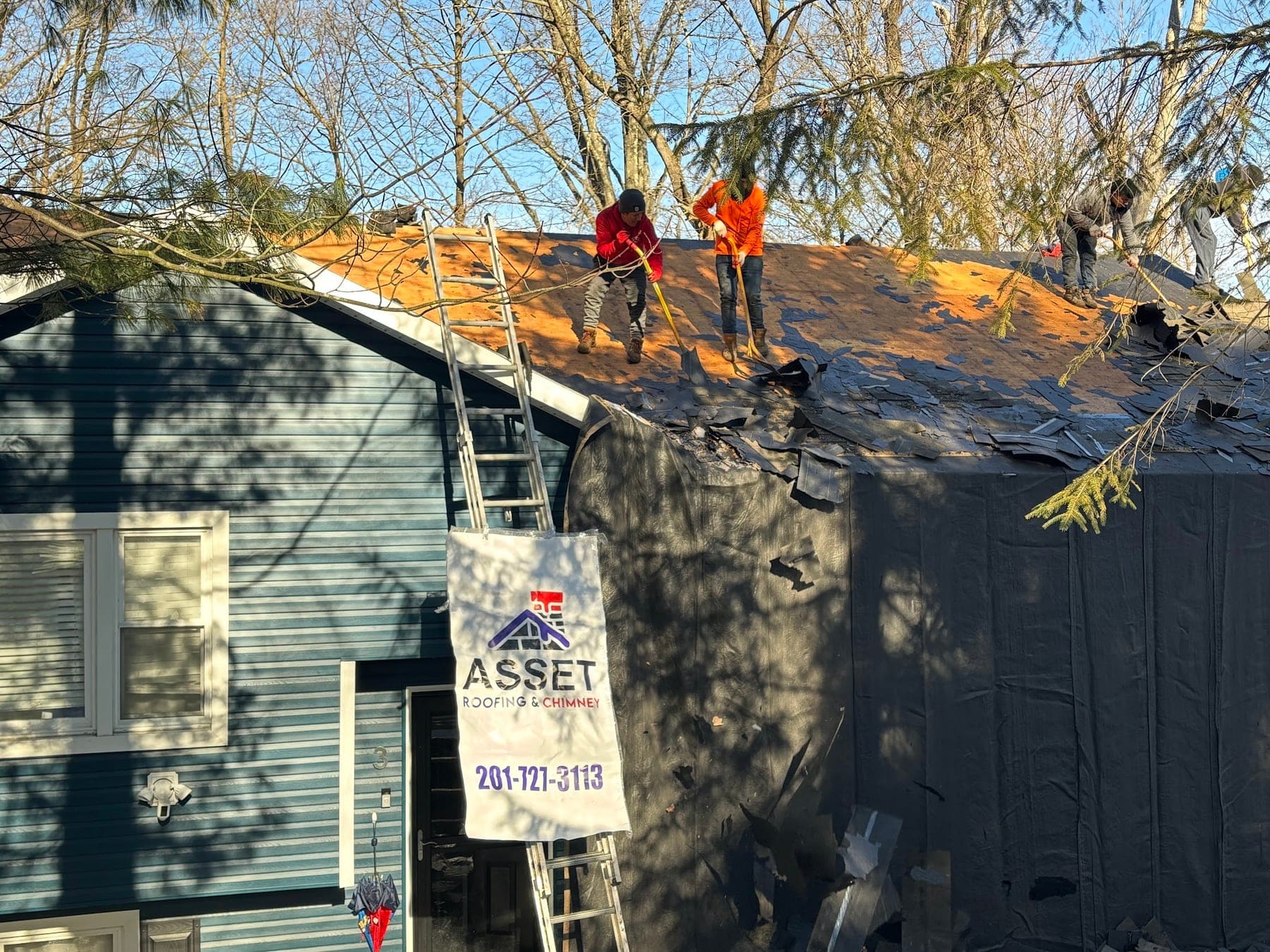 Roof tear-off under way with an Asset Roofing & Chimney yard sign out front