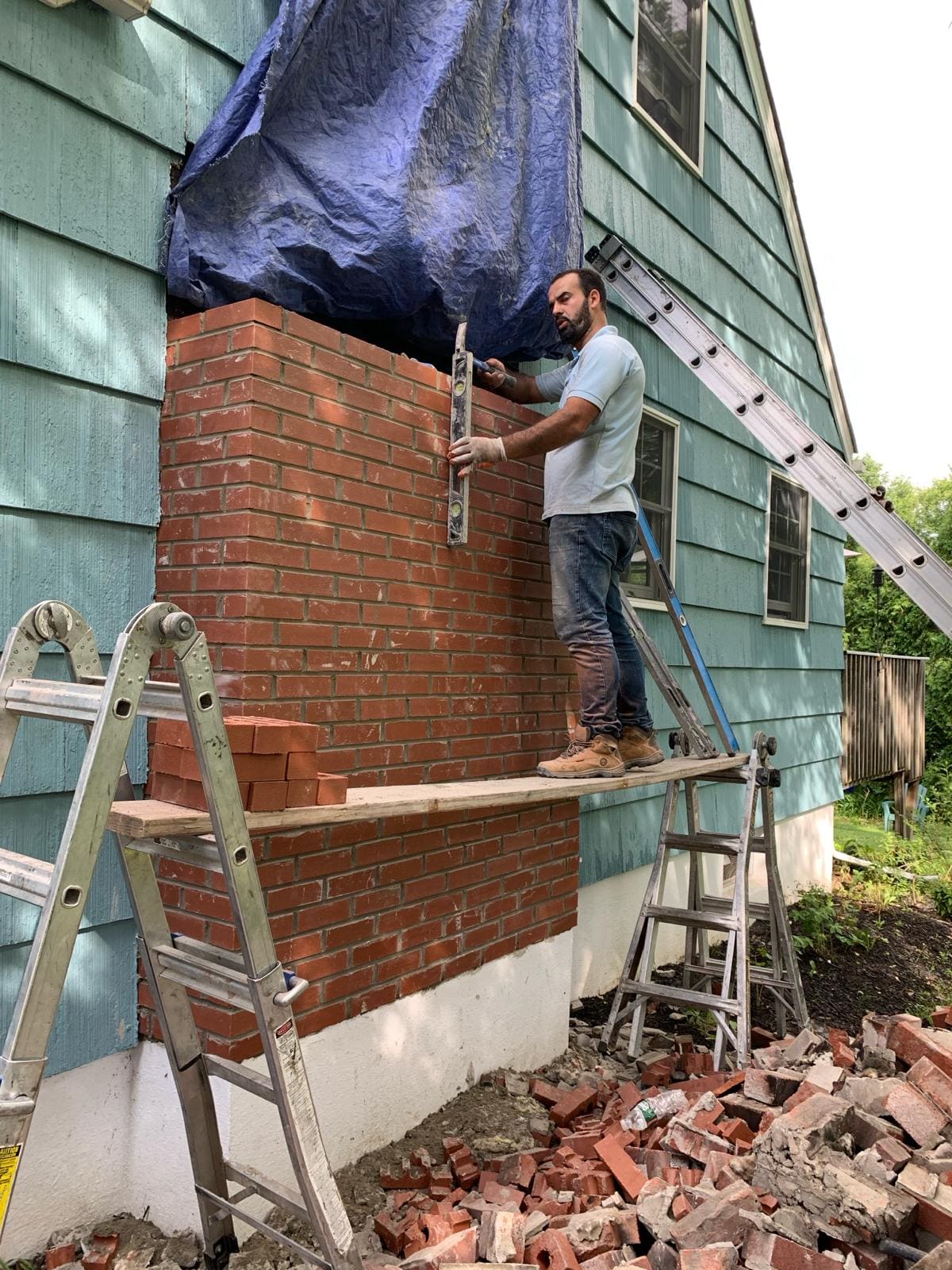 Brick chimney rebuild in progress by an Asset Roofing & Chimney mason